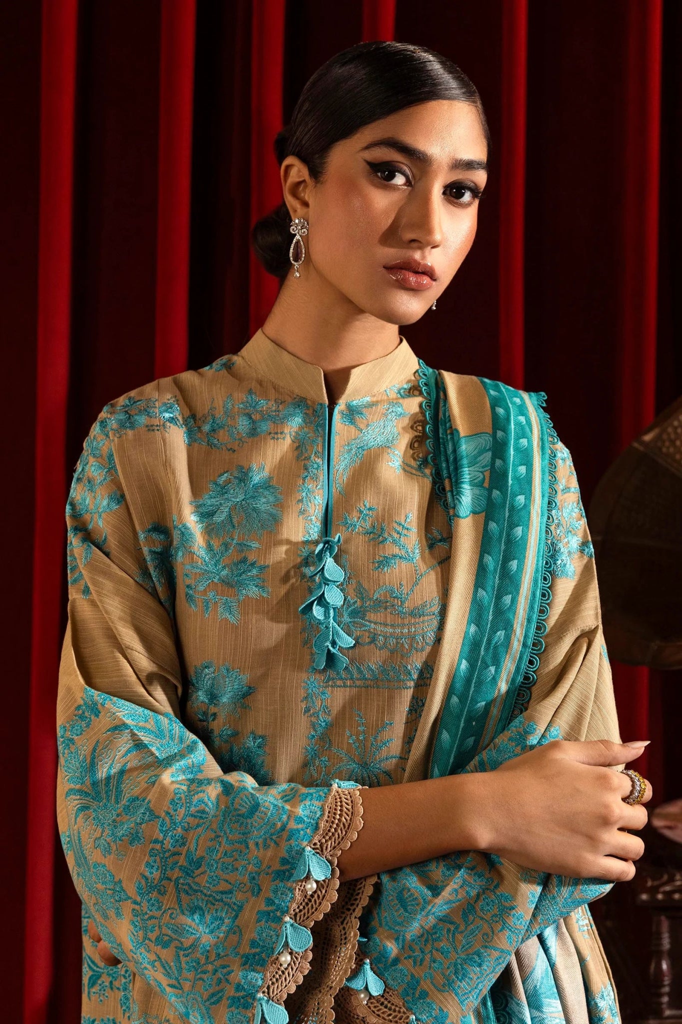 A model wears a three - piece outfit from the Sana Safinaz Muzlin Winter '24 Collection. The ensemble features intricately embroidered front panels on slub fabric, complemented by a printed back and sleeves. It is paired with a matching 2.5 - meter printed shawl and dyed cotton pants, creating a sophisticated winter look. Available online in the UK.