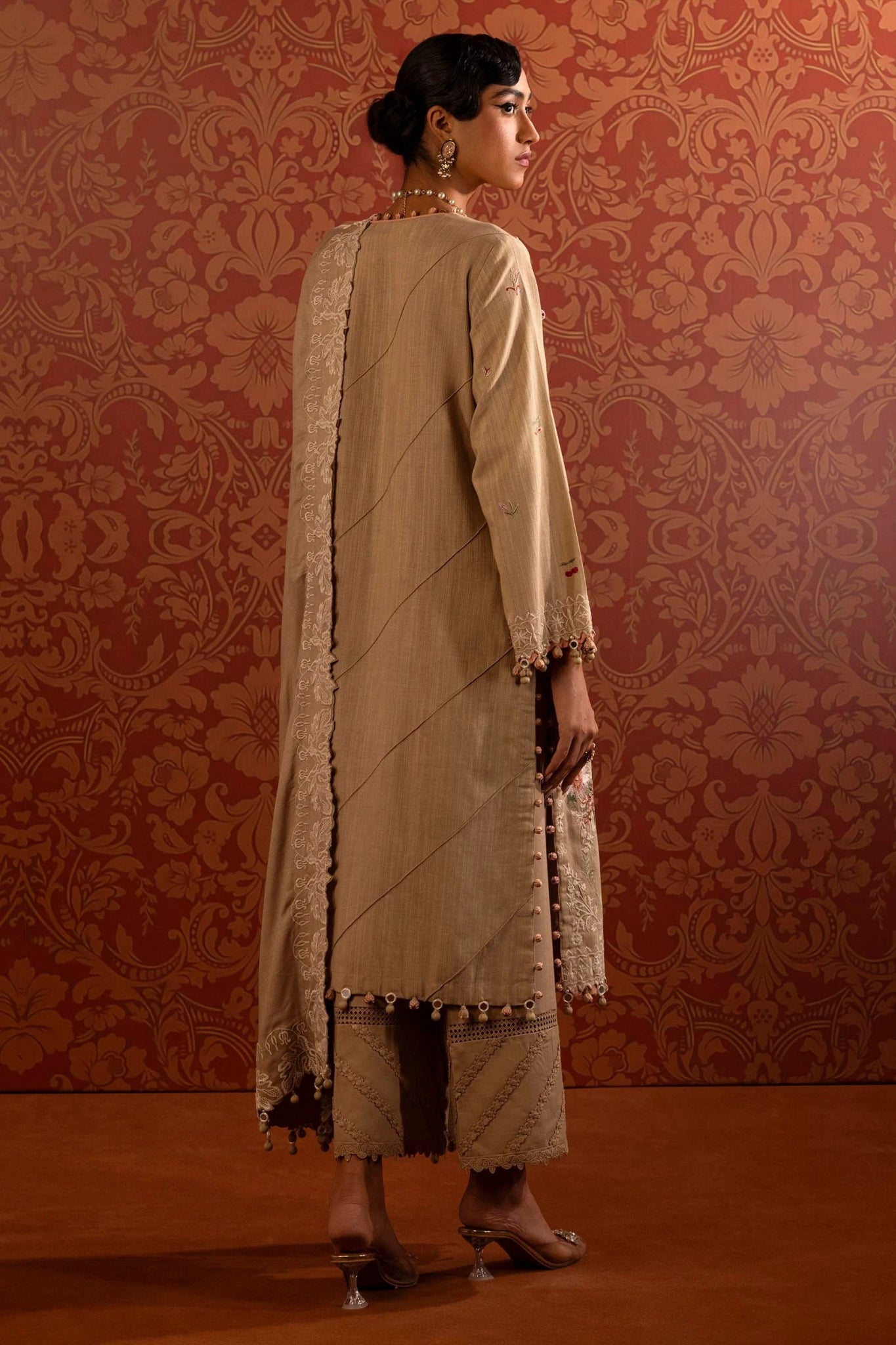 A model wears a three - piece Sana Safinaz outfit from the Muzlin Winter '24 Collection. It features embroidered front panels and sleeves on slub, a matching embroidered shawl with a detailed pallu, and dyed cotton pants. Perfect for women seeking elegant Pakistani designer wear. Available online in the UK.