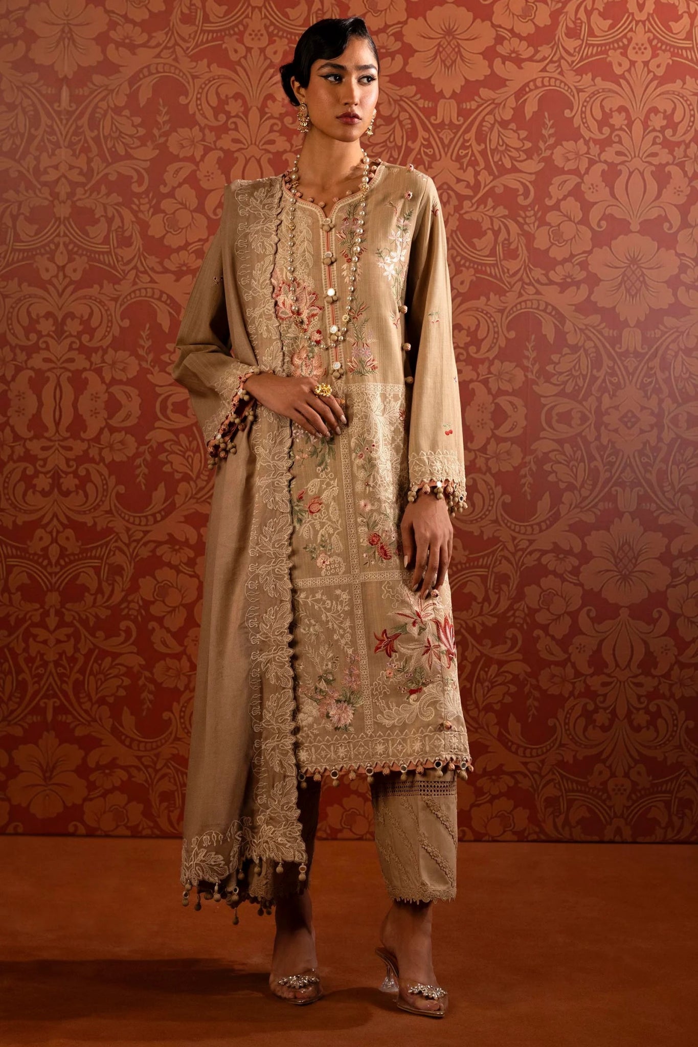 A model wears a three - piece Sana Safinaz outfit from the Muzlin Winter '24 Collection. It features embroidered front panels and sleeves on slub, a matching embroidered shawl with a detailed pallu, and dyed cotton pants. Perfect for women seeking elegant Pakistani designer wear. Available online in the UK.