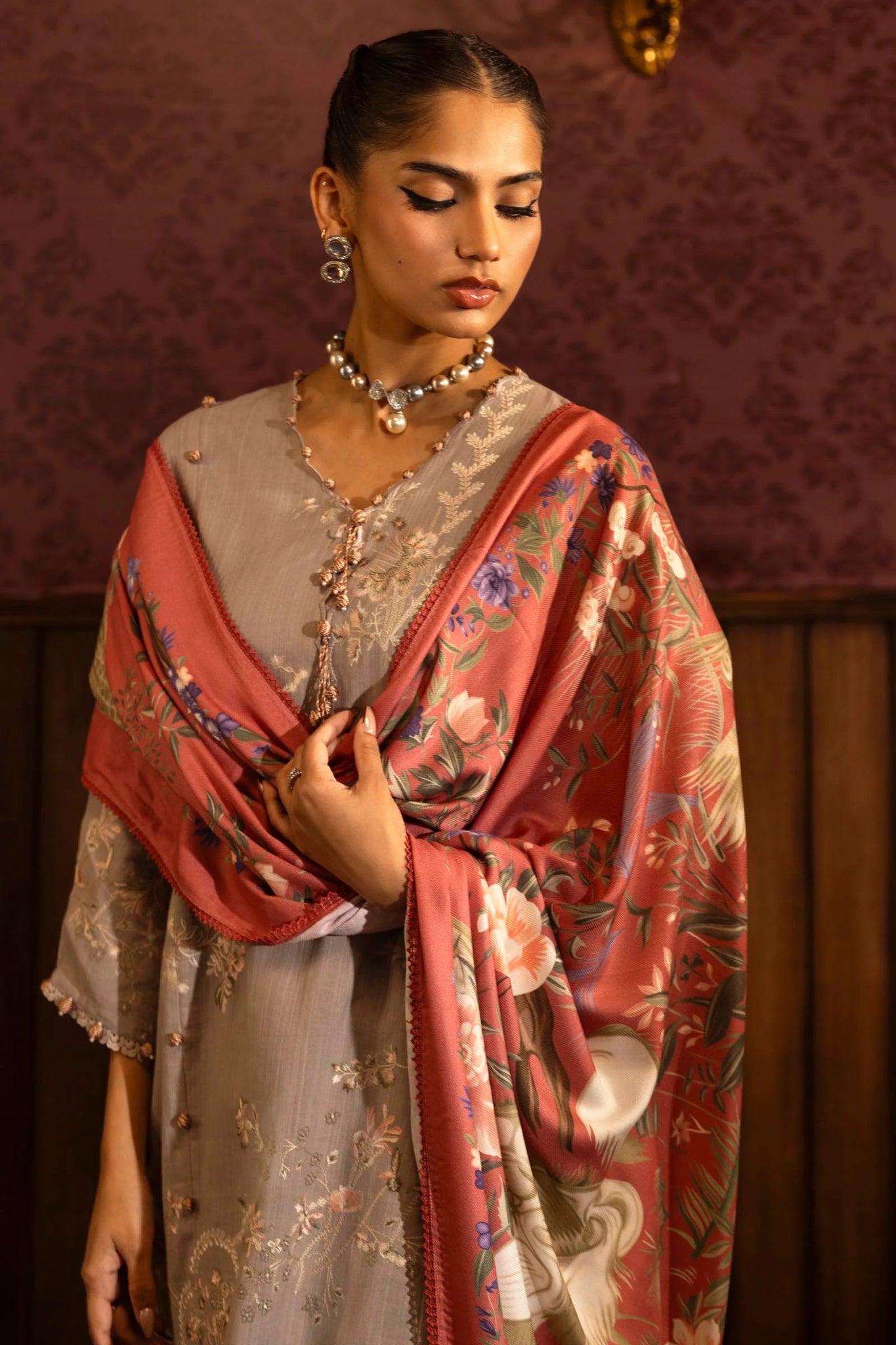 A model wears a three - piece outfit from the Sana Safinaz Muzlin Winter '24 Collection. It features an embroidered front kali on slub, printed back, and embroidered sleeves, paired with a vibrant, digitally printed shawl and matching dyed cotton pants. This elegant look blends traditional embroidery with a modern flair, ideal for women seeking premium Pakistani fashion online in the UK.