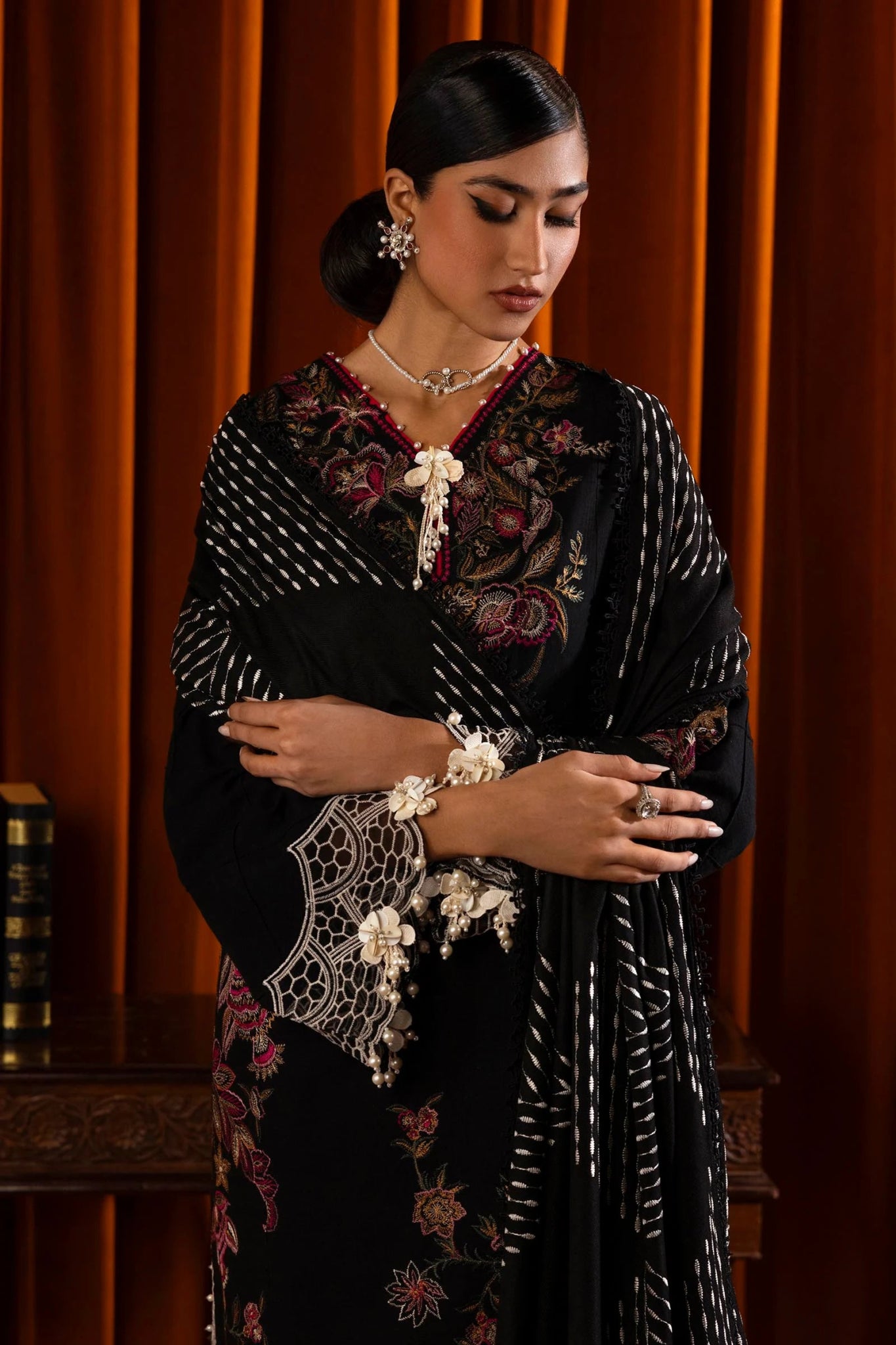 Model wearing a 3 - piece black embroidered suit by a Pakistani designer, featuring a slub front kali, organza kuful details, intricate embroidered shawl, and dyed cotton pants, styled elegantly. Available online in the UK.