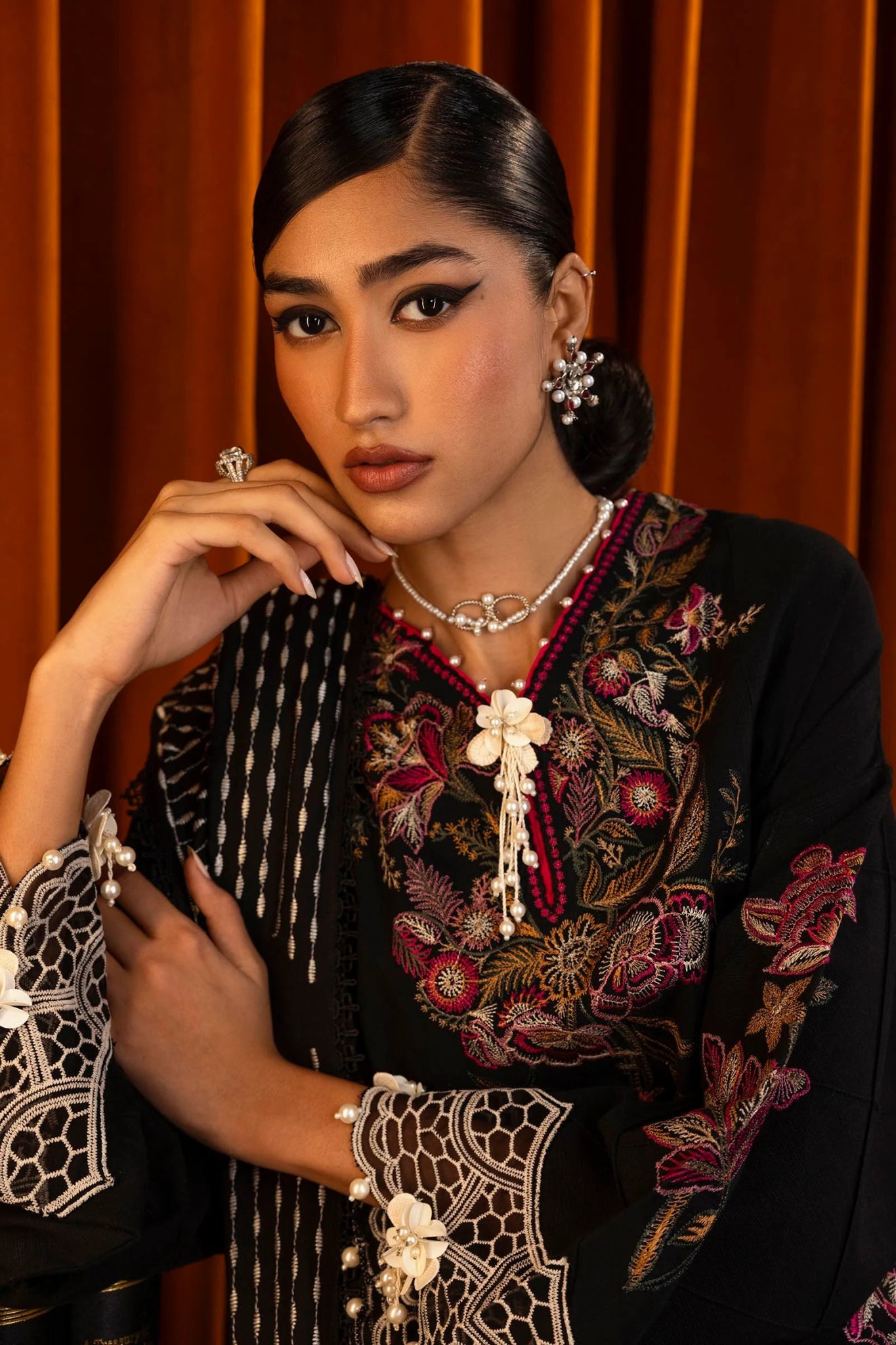 Model wearing a 3 - piece black embroidered suit by a Pakistani designer, featuring a slub front kali, organza kuful details, intricate embroidered shawl, and dyed cotton pants, styled elegantly. Available online in the UK.