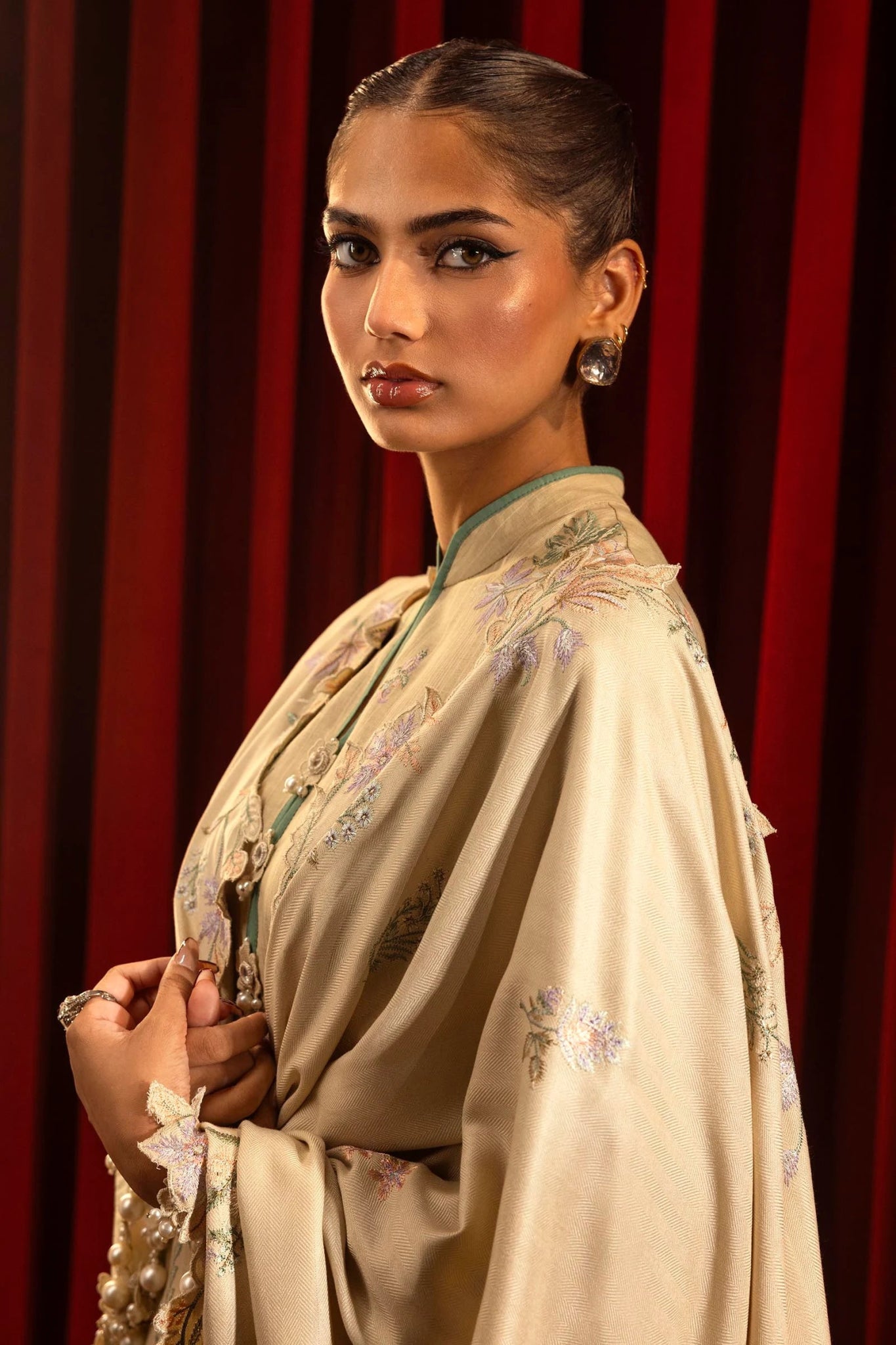 Model wearing a 3 - piece beige embroidered suit featuring a slub front kali, printed back and sleeves, and a shawl with embroidered organza pallu. Paired with dyed cotton pants for an elegant look. Part of the Sana Safinaz Muzlin Winter 2024 collection, available online in the UK.