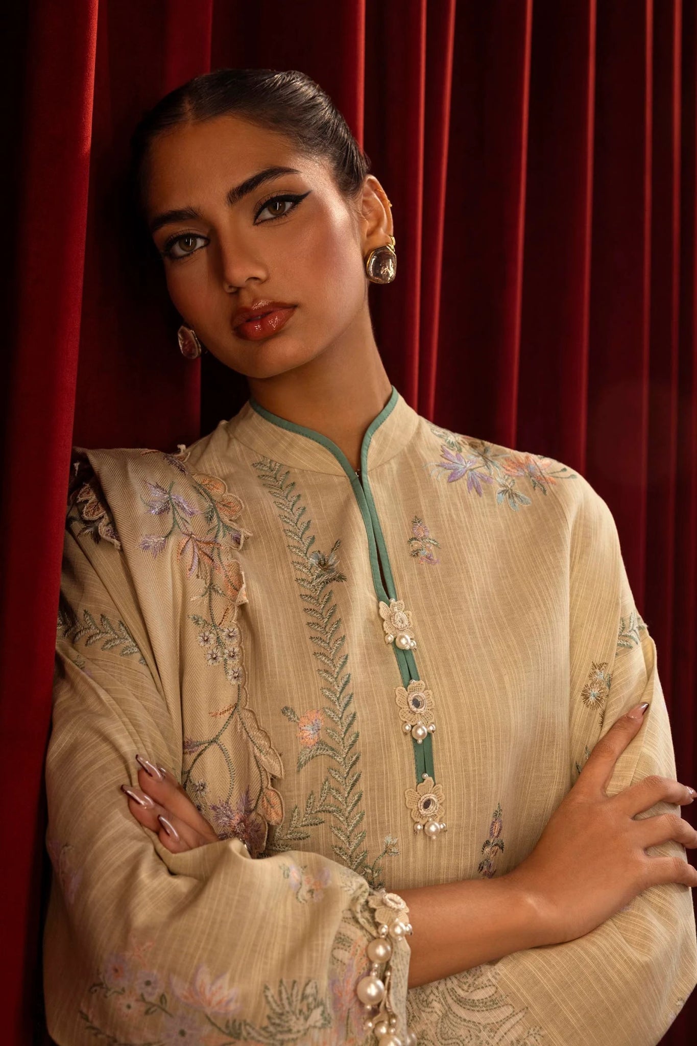 Model wearing a 3 - piece beige embroidered suit featuring a slub front kali, printed back and sleeves, and a shawl with embroidered organza pallu. Paired with dyed cotton pants for an elegant look. Part of the Sana Safinaz Muzlin Winter 2024 collection, available online in the UK.