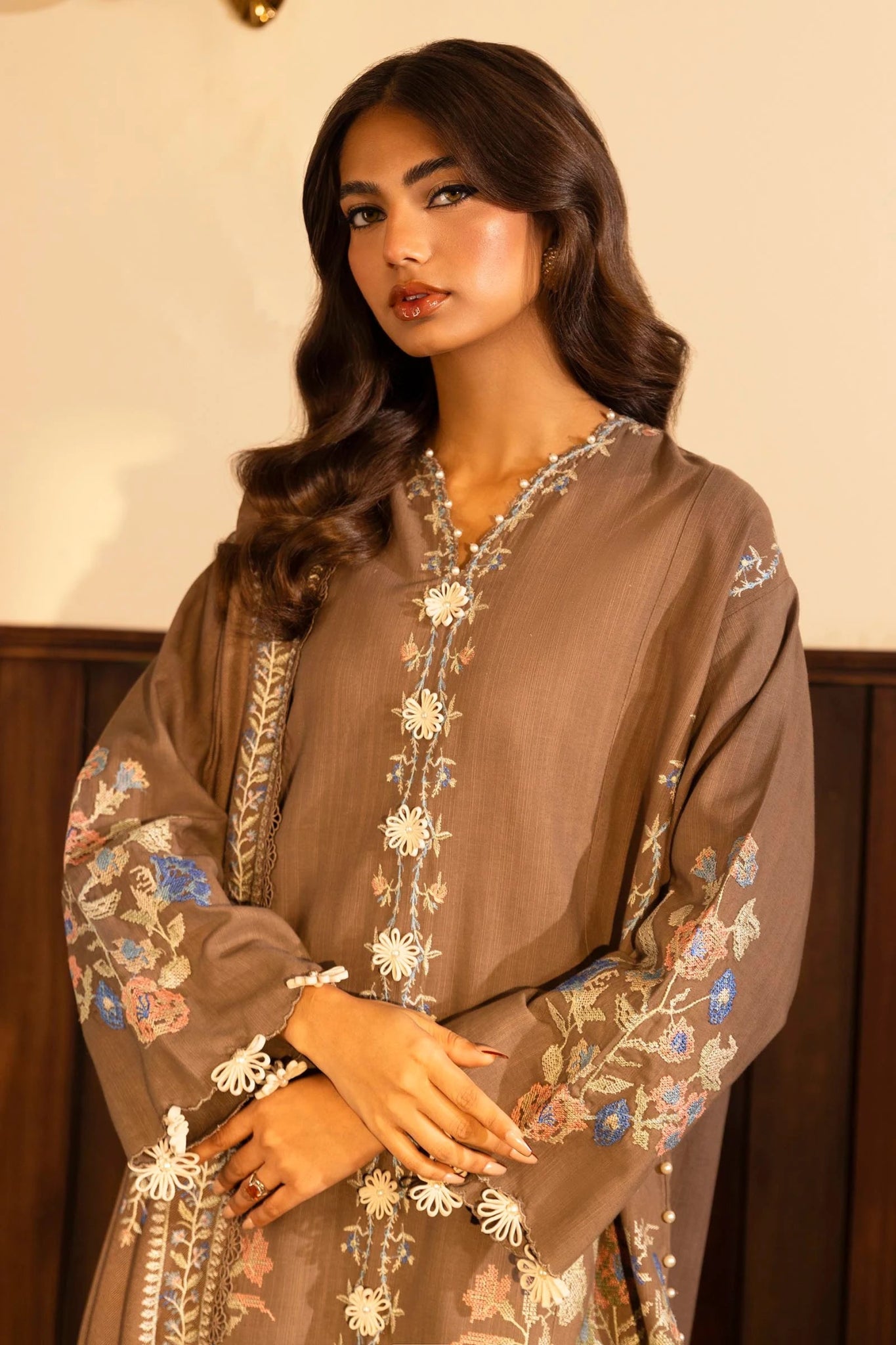 Model wearing a 3 - piece taupe embroidered suit featuring a slub front kali, dyed sleeves with organza kuful, and a shawl with embroidered organza pallu. Paired with dyed cotton pants for an elegant look. Part of the Sana Safinaz Muzlin Winter 2024 collection, available online in the UK.