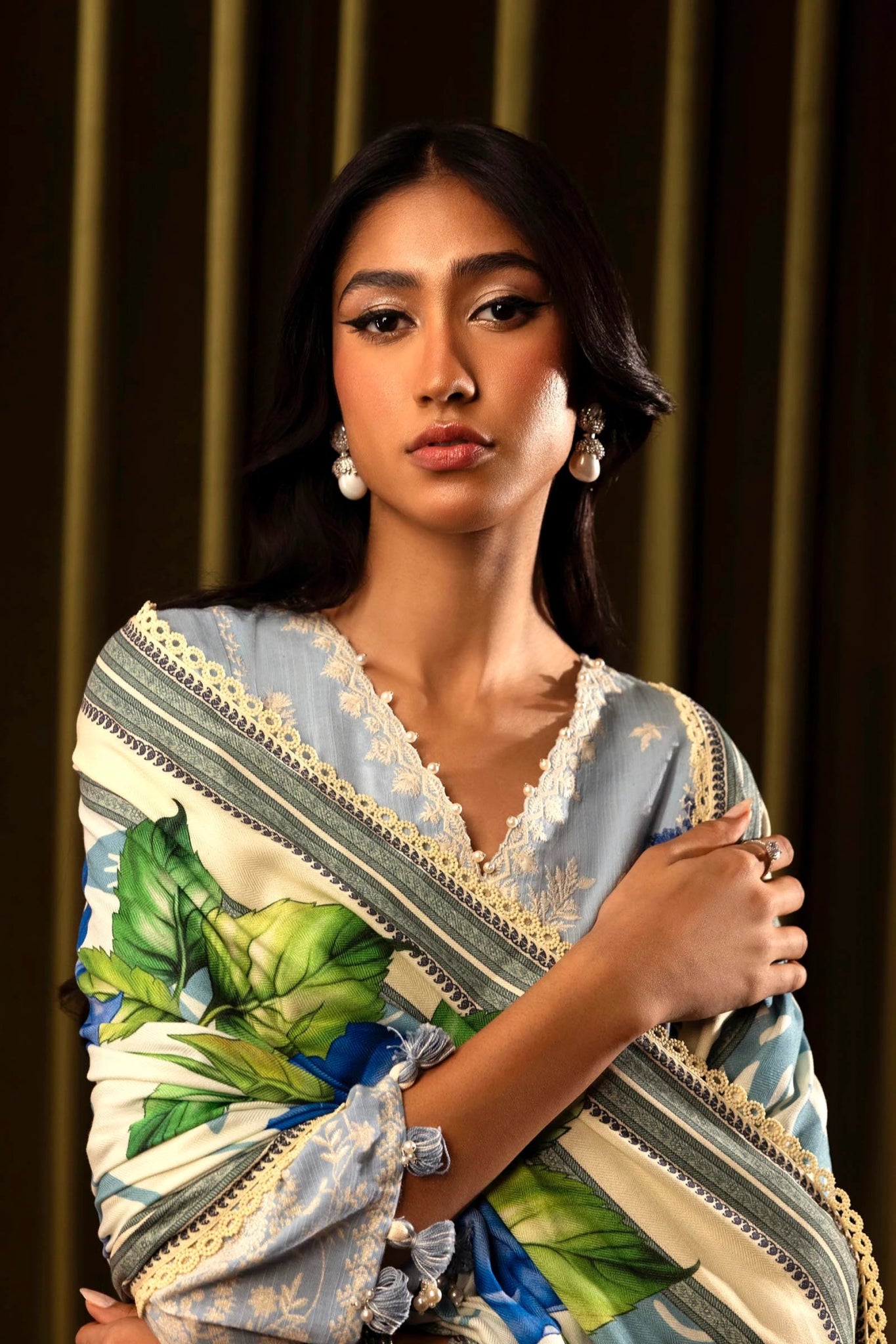 Model wearing a 3 - piece light blue embroidered suit featuring a slub front kali, printed back and sleeves, and a digital printed shawl with floral patterns. Paired with dyed cotton pants for an elegant look. Part of the Sana Safinaz Muzlin Winter 2024 collection, available online in the UK.