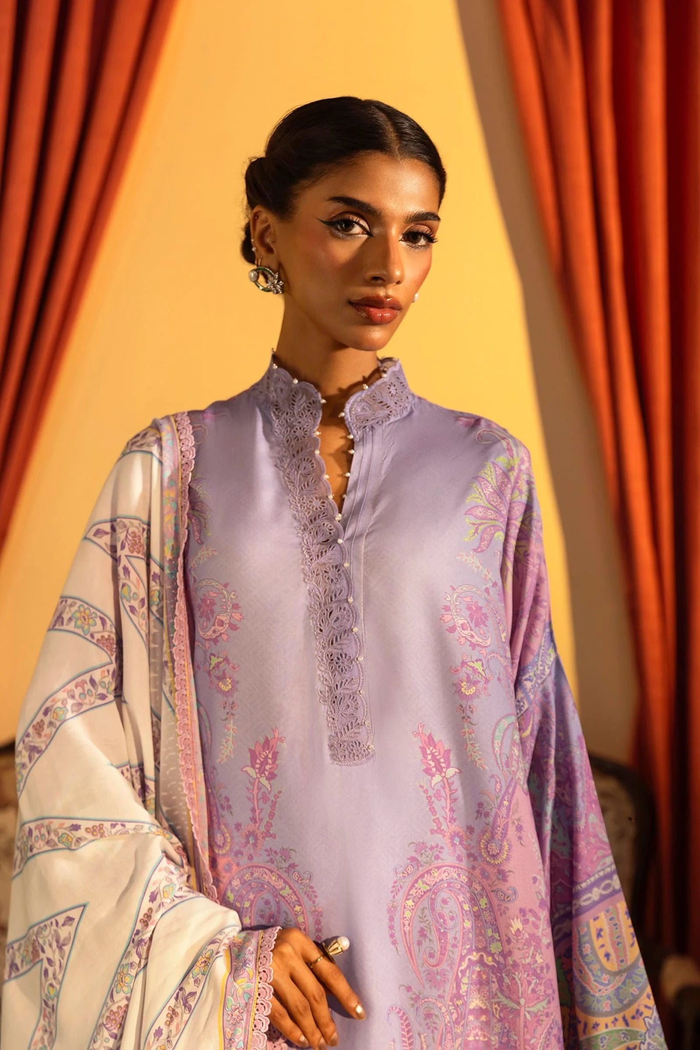 Model wearing a 3 - piece lavender suit featuring a digitally printed linen front, back, and sleeves with intricate patterns, paired with a matching printed dupatta. Styled with dyed cotton pants for an elegant look. Part of the Sana Safinaz Muzlin Winter 2024 collection, available online in the UK.