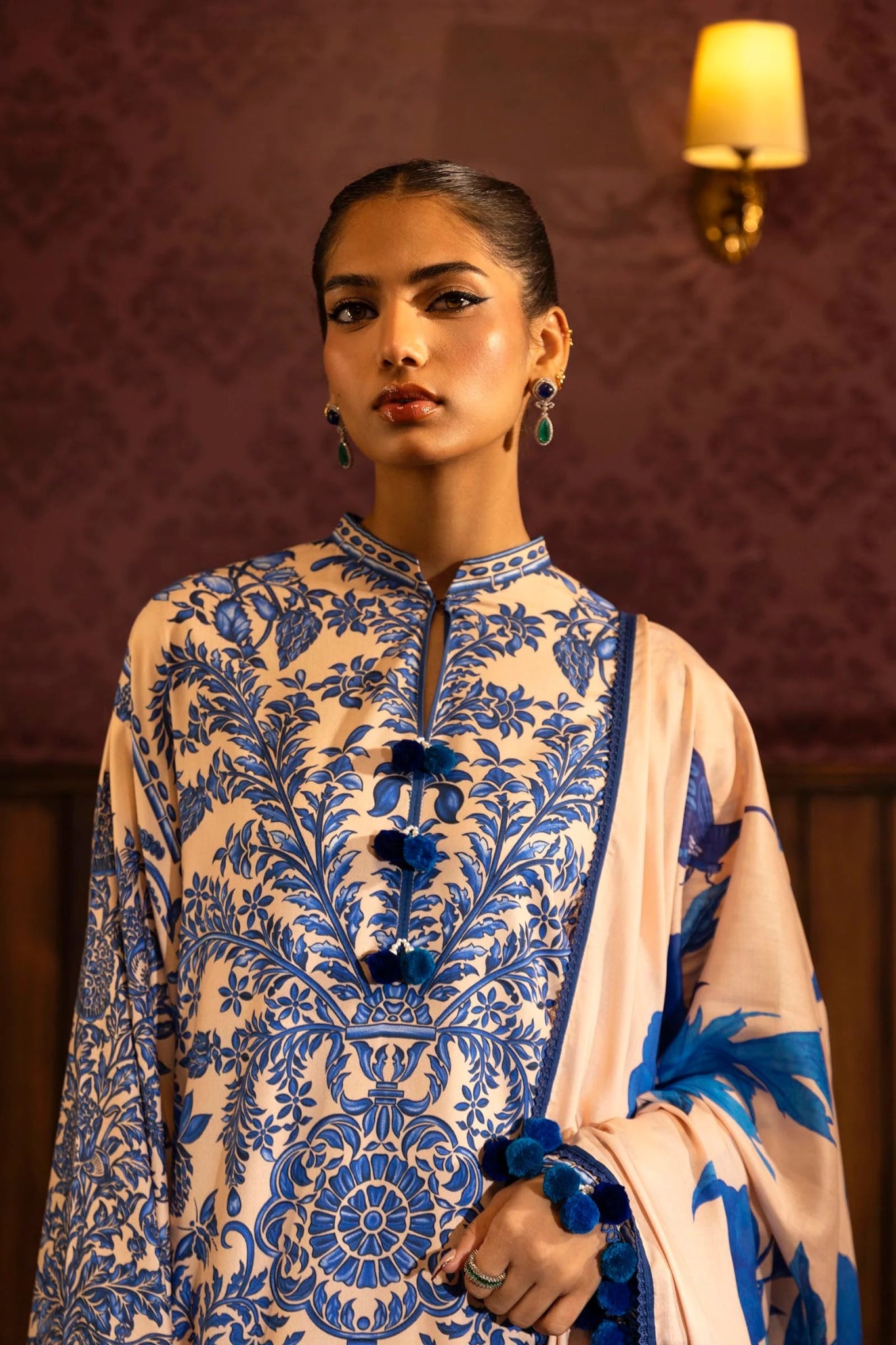 Model wearing a 3 - piece cream and blue suit featuring a digitally printed linen front, back, and sleeves with intricate patterns. Styled with embroidered organza sleeve borders, a printed linen dupatta, and dyed cotton pants with floral embroidery. Part of the Sana Safinaz Muzlin Winter 2024 collection, available online in the UK.