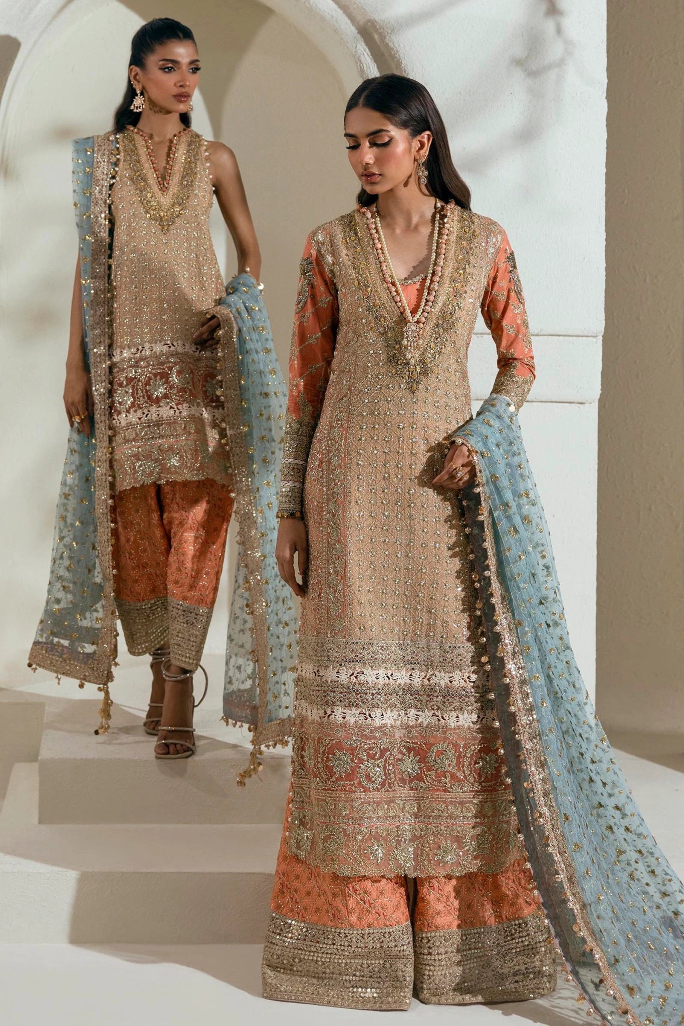 Model wearing a gold and orange Sana Safinaz NURA Festive'24 Vol. II N242 - 002 - 3CX dress with intricate embroidery and a blue dupatta. Perfect for weddings and available online in the UK.