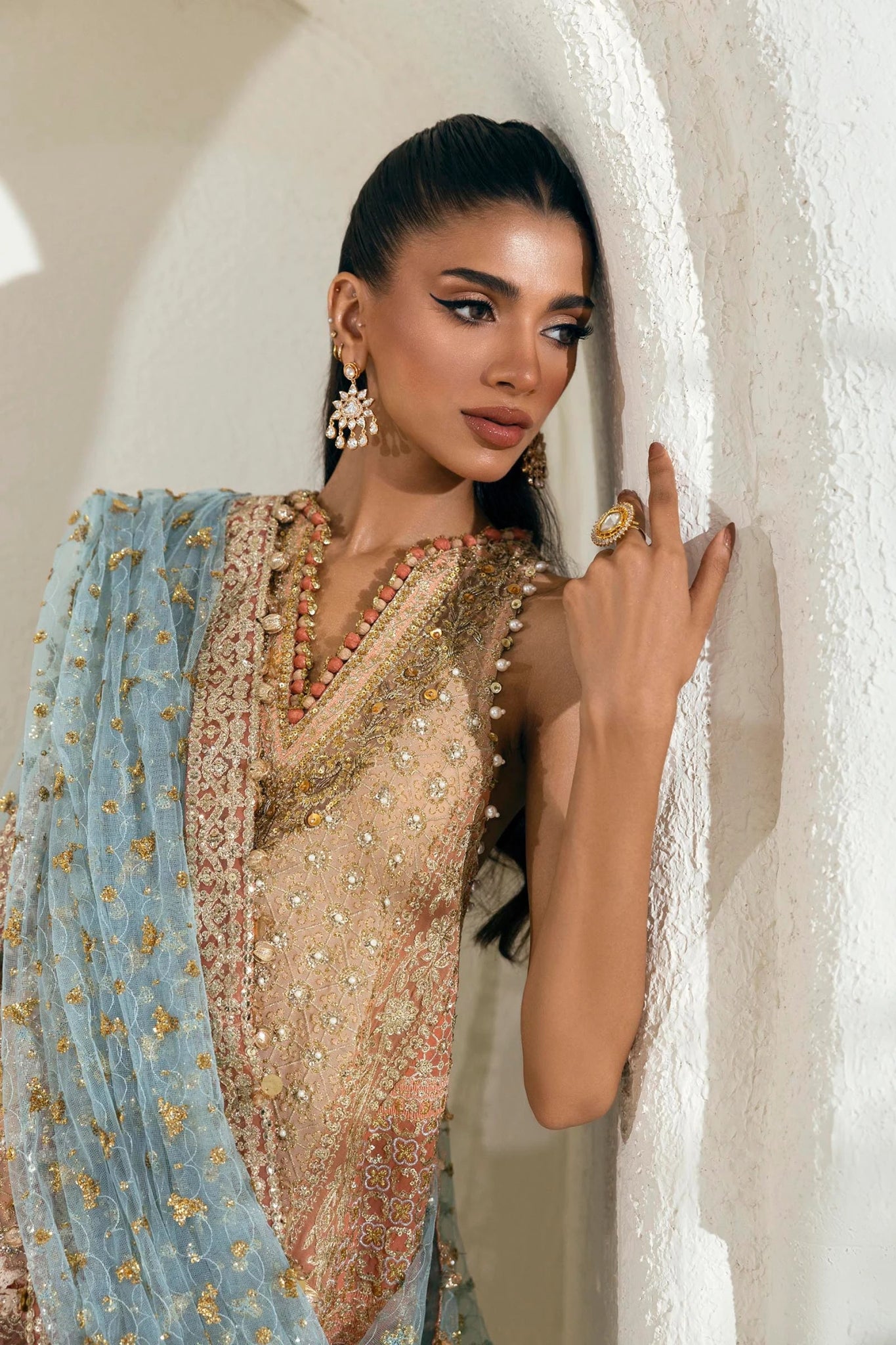 Model wearing a gold and orange Sana Safinaz NURA Festive'24 Vol. II N242 - 002 - 3CX dress with intricate embroidery and a blue dupatta. Perfect for weddings and available online in the UK.