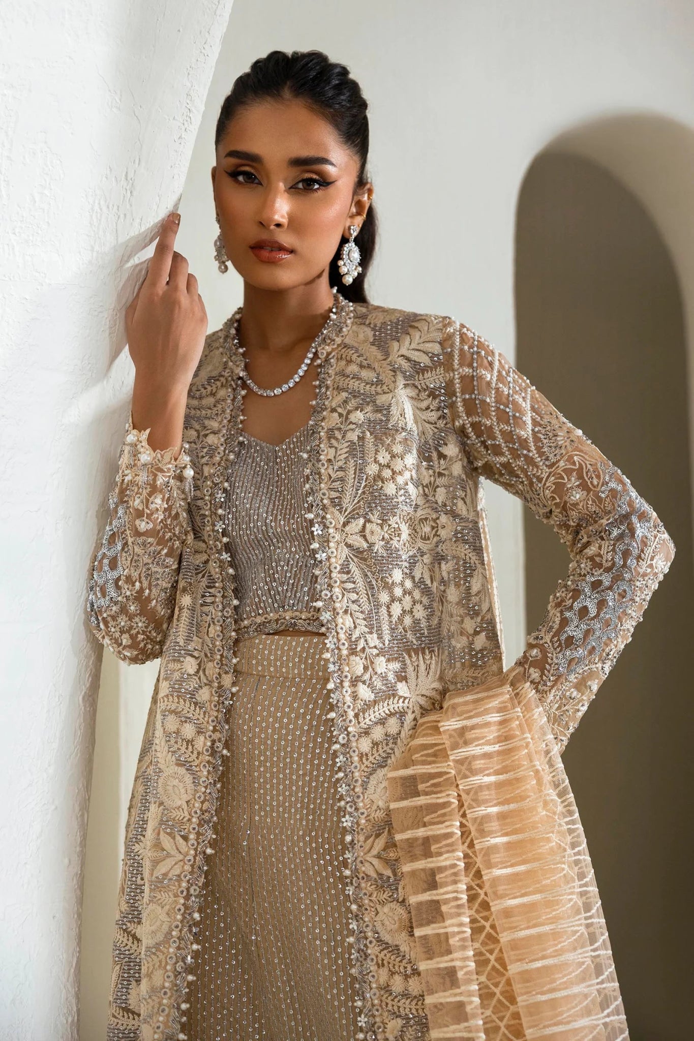 Model wearing an elegant N242 - 005 - 3CT dress in beige and gold from Sana Safinaz's NURA Festive '24 Vol. II collection. Available for Pakistani clothes online in UK, perfect for wedding clothes.