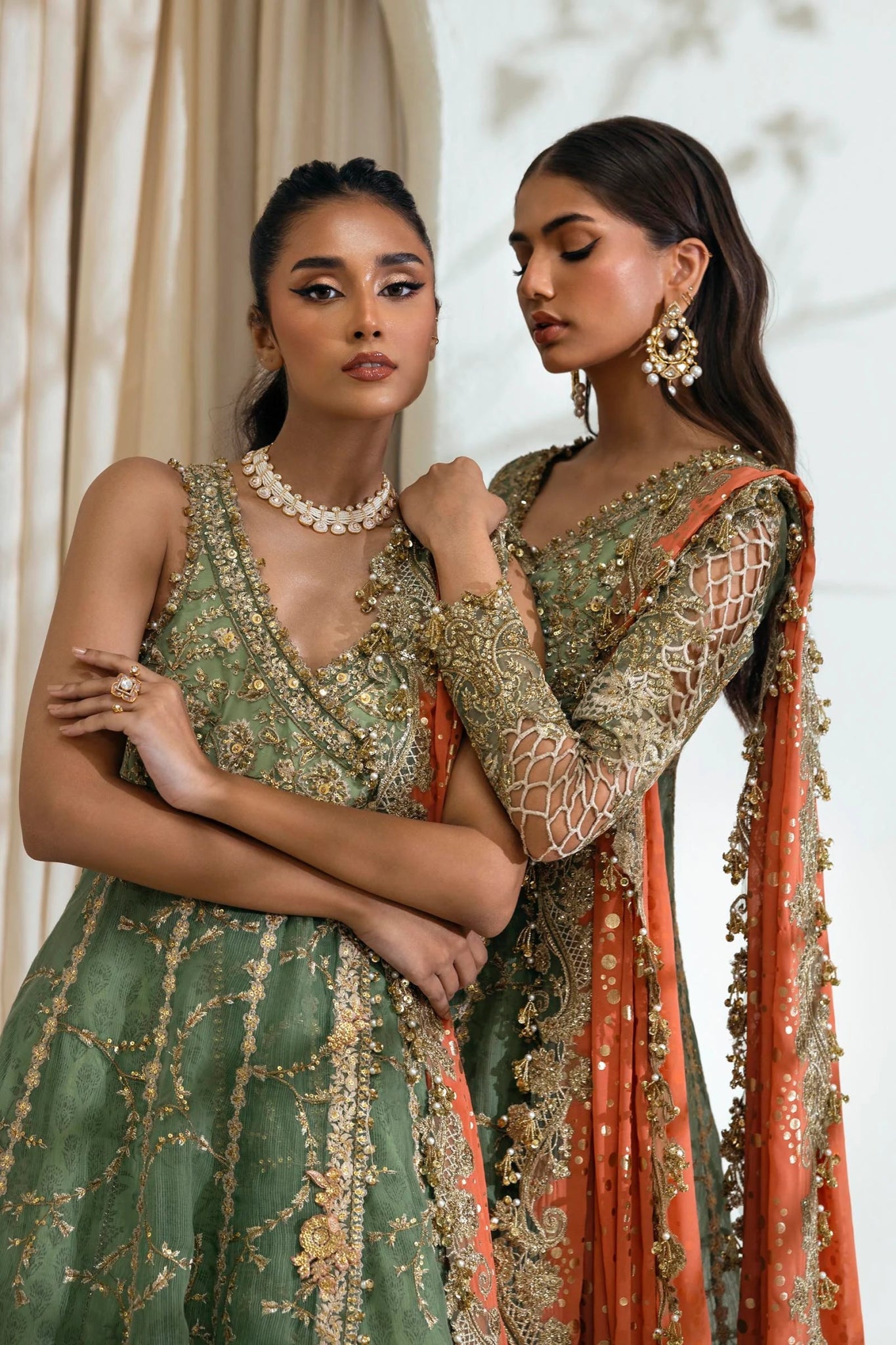 Model wearing Sana Safinaz NURA Festive'24 Vol. II N242 - 006 - 3CX dress, featuring a green ensemble with gold embellishments and an orange dupatta. Perfect for weddings and available as Pakistani clothes online in the UK.