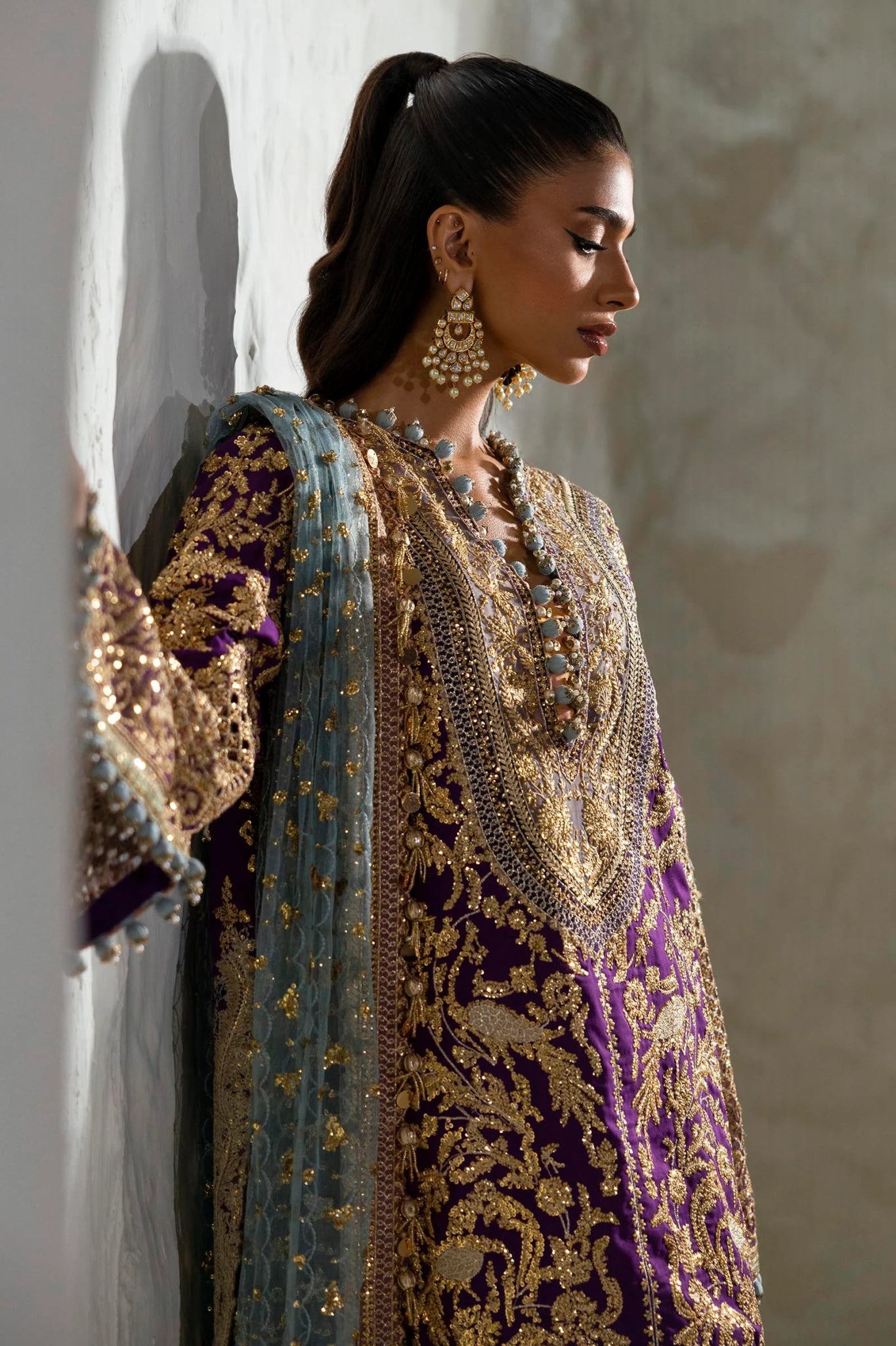 Model wearing a Sana Safinaz NURA Festive'24 Vol. II N242 - 007 - 3CX purple and gold embroidered dress with a blue dupatta. Perfect for Pakistani clothes online in UK, wedding clothes.