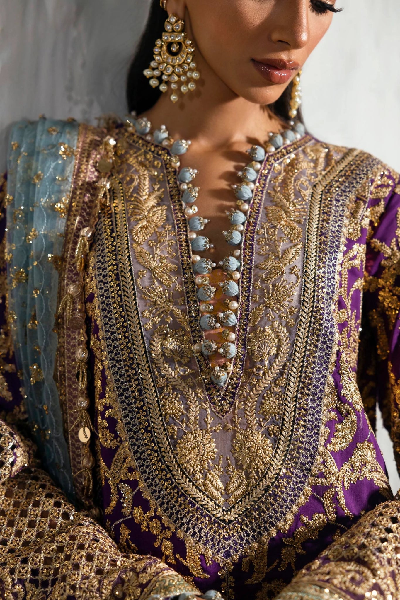 Model wearing a Sana Safinaz NURA Festive'24 Vol. II N242 - 007 - 3CX purple and gold embroidered dress with a blue dupatta. Perfect for Pakistani clothes online in UK, wedding clothes.