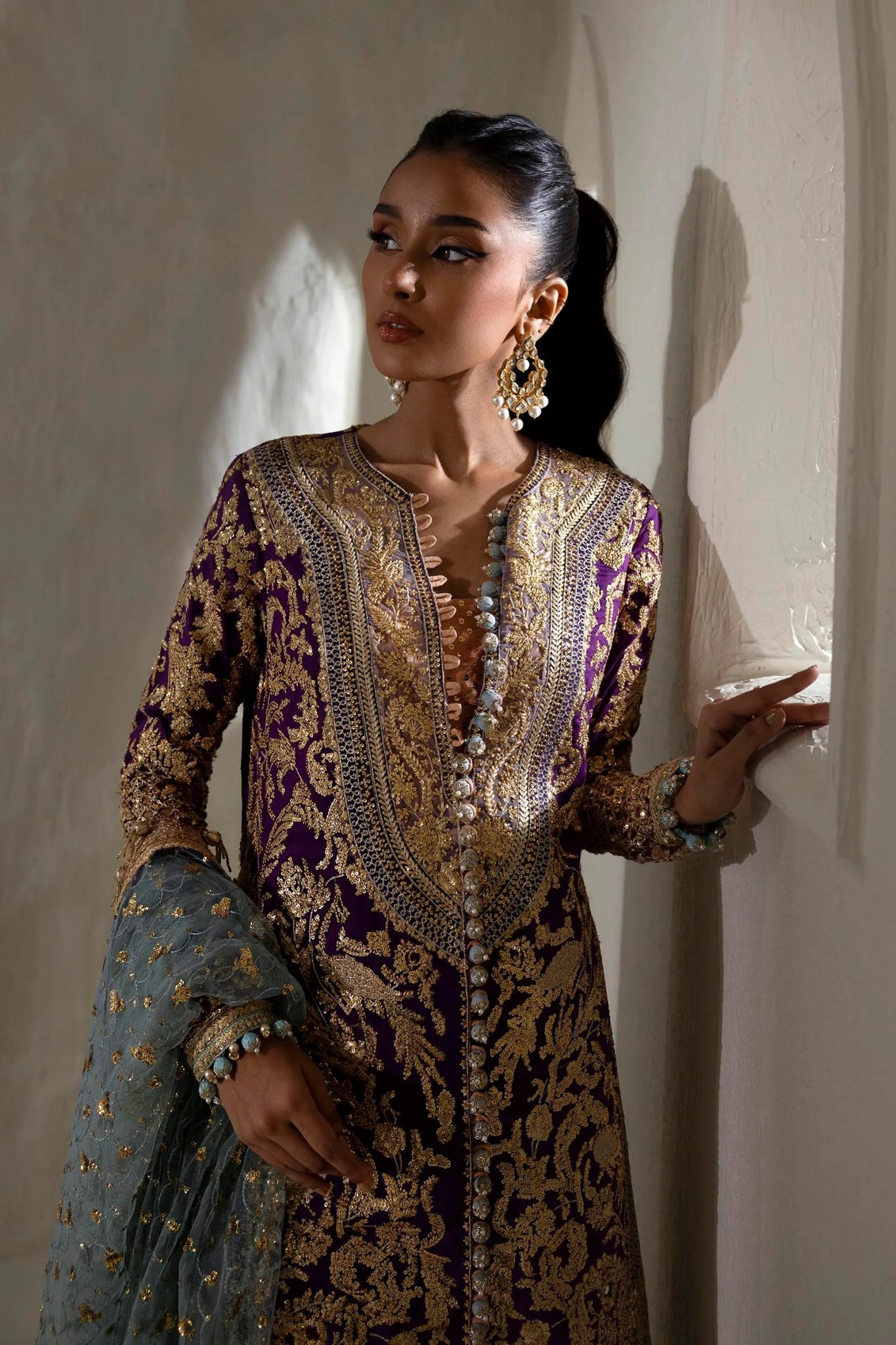 Model wearing a Sana Safinaz NURA Festive'24 Vol. II N242 - 007 - 3CX purple and gold embroidered dress with a blue dupatta. Perfect for Pakistani clothes online in UK, wedding clothes.