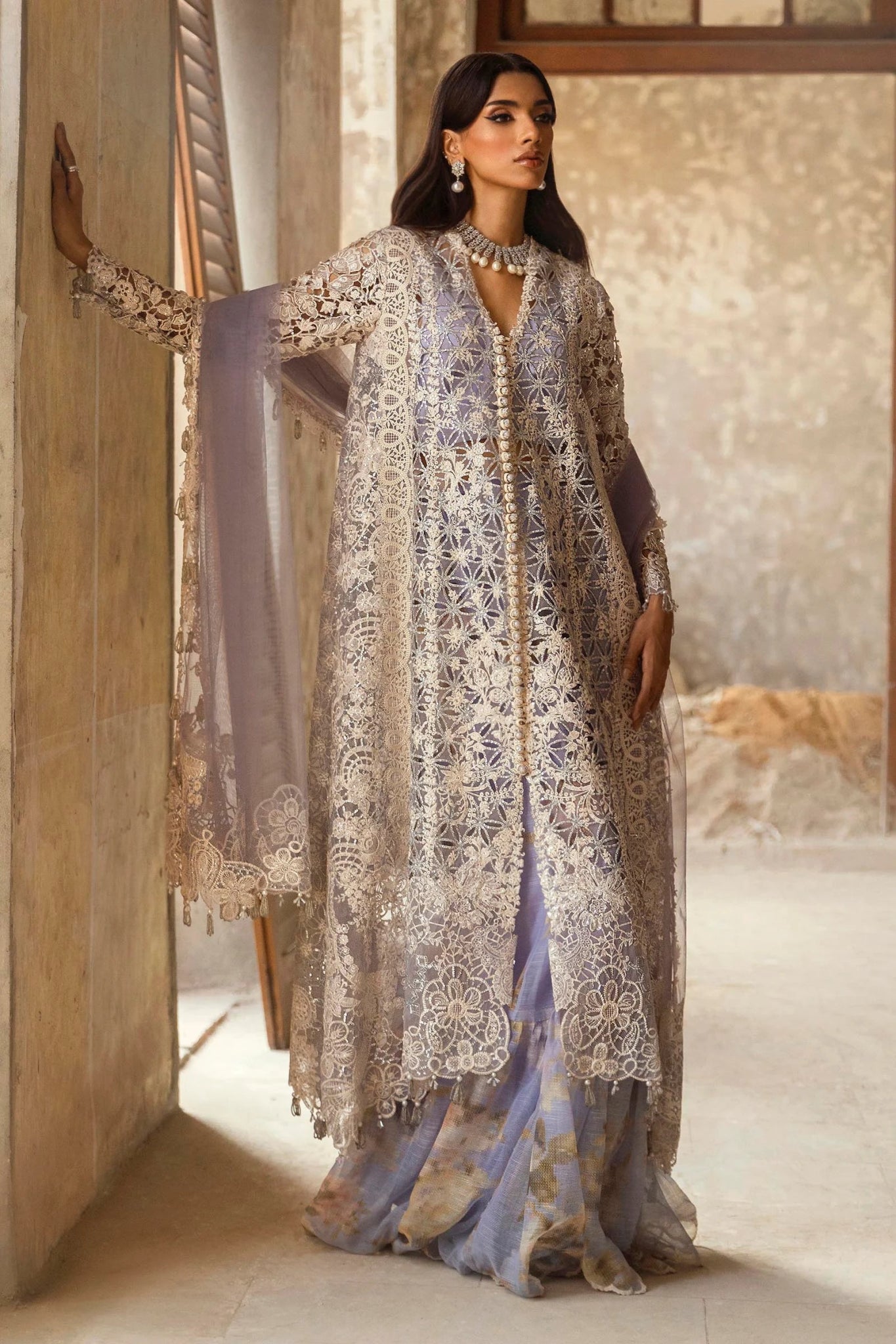 A stunning model showcasing a Sana Safinaz Nura Vol. 3 2024 lavender outfit with hand - embellished cutwork on organza, embroidered dupatta, and a digitally printed woven net lehenga. Perfect for formal occasions, this Pakistani luxury pret wear is available online in the UK exclusively at Signature Labels.