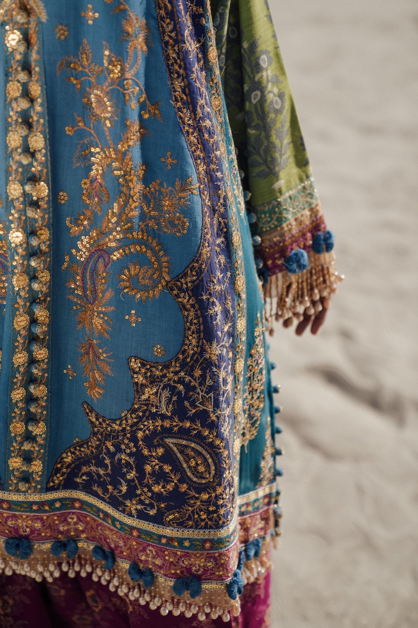 Model wearing Sana Safinaz Winter Luxury '24 S241 - 002B - 3CP, a vibrant blue and green embroidered ensemble with intricate gold details, ideal for winter. Perfect for Pakistani clothes online in the UK.