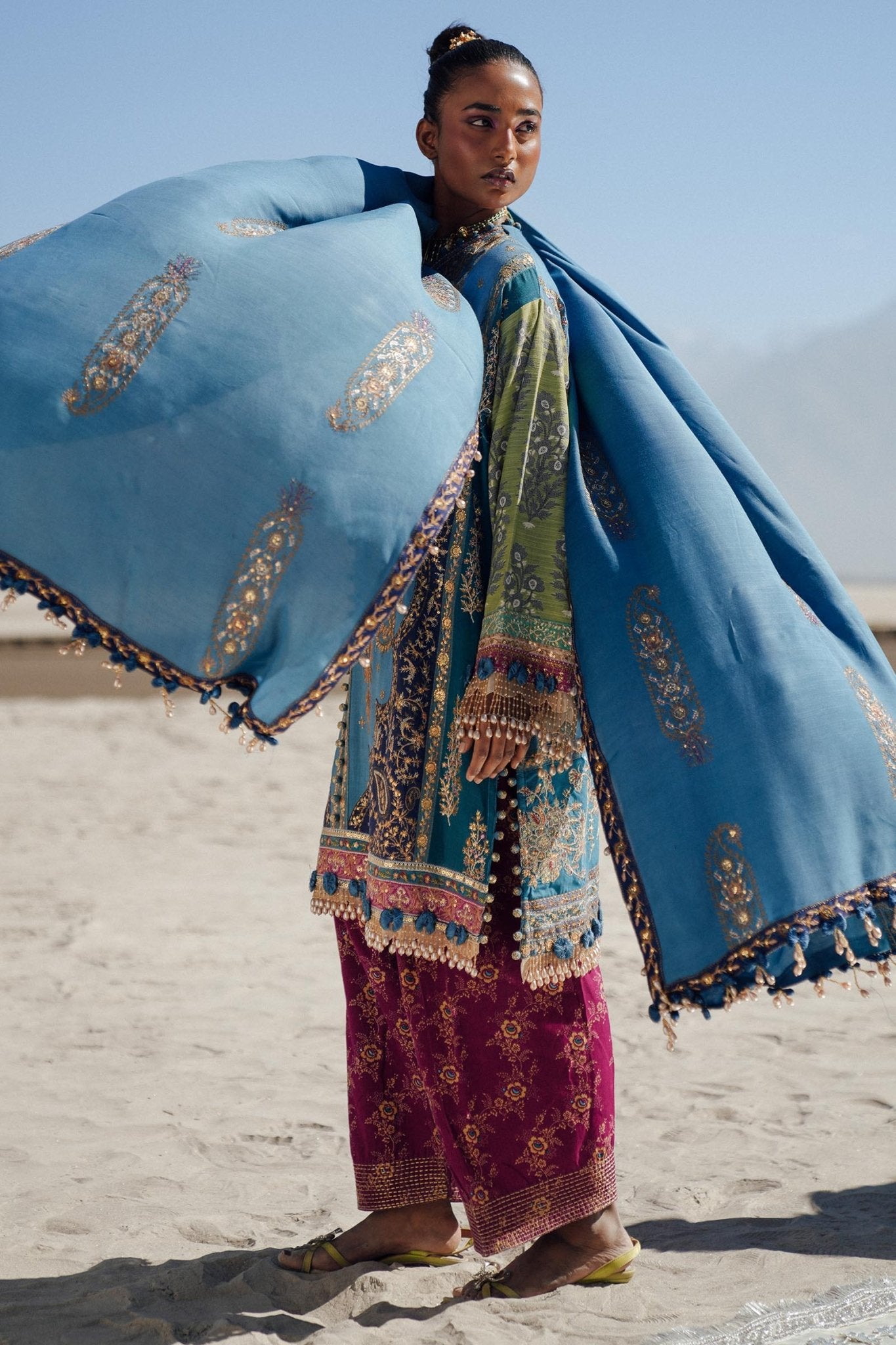 Model wearing Sana Safinaz Winter Luxury '24 S241 - 002B - 3CP, a vibrant blue and green embroidered ensemble with intricate gold details, ideal for winter. Perfect for Pakistani clothes online in the UK.