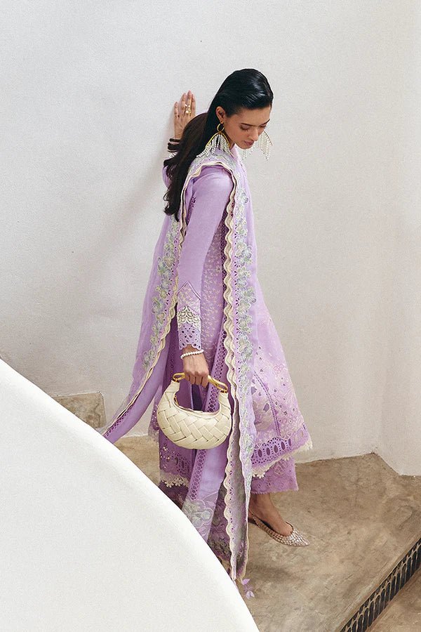 Model is wearing a lilac panelled jacquard shirt with floral embroidery, patchwork, and a crown - shaped organza neckline from Suffuse's Fall Casual Pret '24. Paired with straight cotton pants featuring lace details and cutwork finesse. The chiffon dupatta has organza borders and abstract prints. Available in the UK.