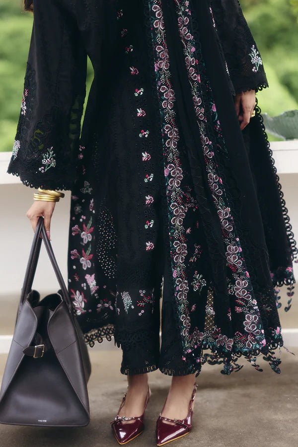 Model wearing a black jacquard front open A - line kurta with pastel floral embroidery, wide sleeves, and a printed raw silk neckline. Paired with black straight pants featuring lace detailing and a chiffon dupatta with embroidered borders and geometric patterns. This look is from Suffuse's Fall Casual Pret 24 Collection.