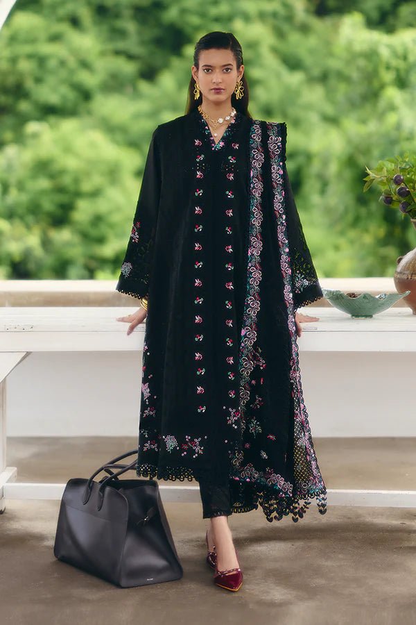 Model wearing a black jacquard front open A - line kurta with pastel floral embroidery, wide sleeves, and a printed raw silk neckline. Paired with black straight pants featuring lace detailing and a chiffon dupatta with embroidered borders and geometric patterns. This look is from Suffuse's Fall Casual Pret 24 Collection.