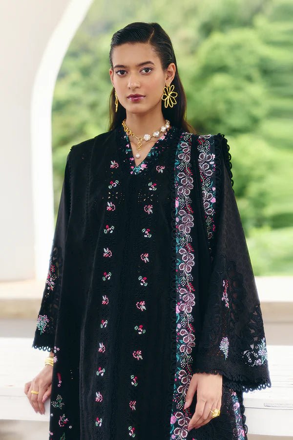 Model wearing a black jacquard front open A - line kurta with pastel floral embroidery, wide sleeves, and a printed raw silk neckline. Paired with black straight pants featuring lace detailing and a chiffon dupatta with embroidered borders and geometric patterns. This look is from Suffuse's Fall Casual Pret 24 Collection.