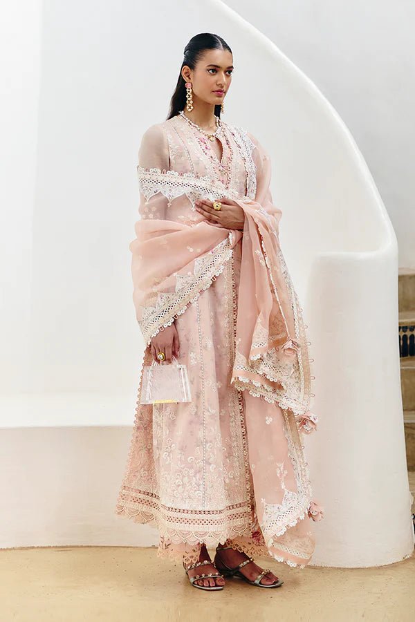 Model wearing a pastel peach flared overlapped double - layered shirt from Suffuse Casual Pret '24 collection, featuring white embroidery and lace detailing. Paired with printed cotton culottes and an organza dupatta. Available online in the UK.