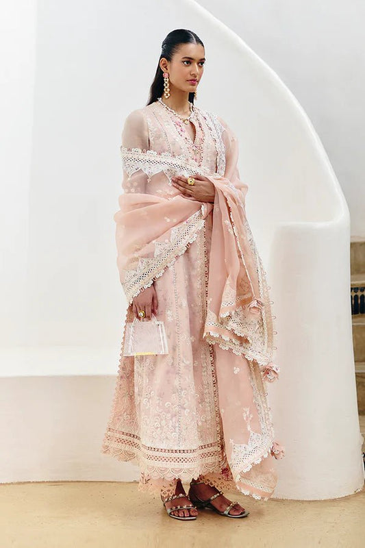 Model wearing a pastel peach flared overlapped double - layered shirt from Suffuse Casual Pret '24 collection, featuring white embroidery and lace detailing. Paired with printed cotton culottes and an organza dupatta. Available online in the UK.