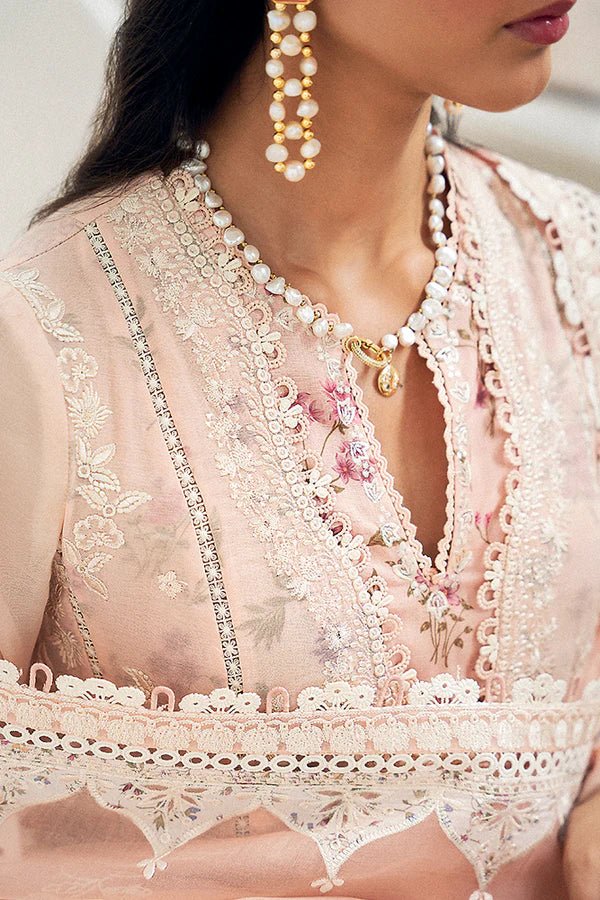 Model wearing a pastel peach flared overlapped double - layered shirt from Suffuse Casual Pret '24 collection, featuring white embroidery and lace detailing. Paired with printed cotton culottes and an organza dupatta. Available online in the UK.