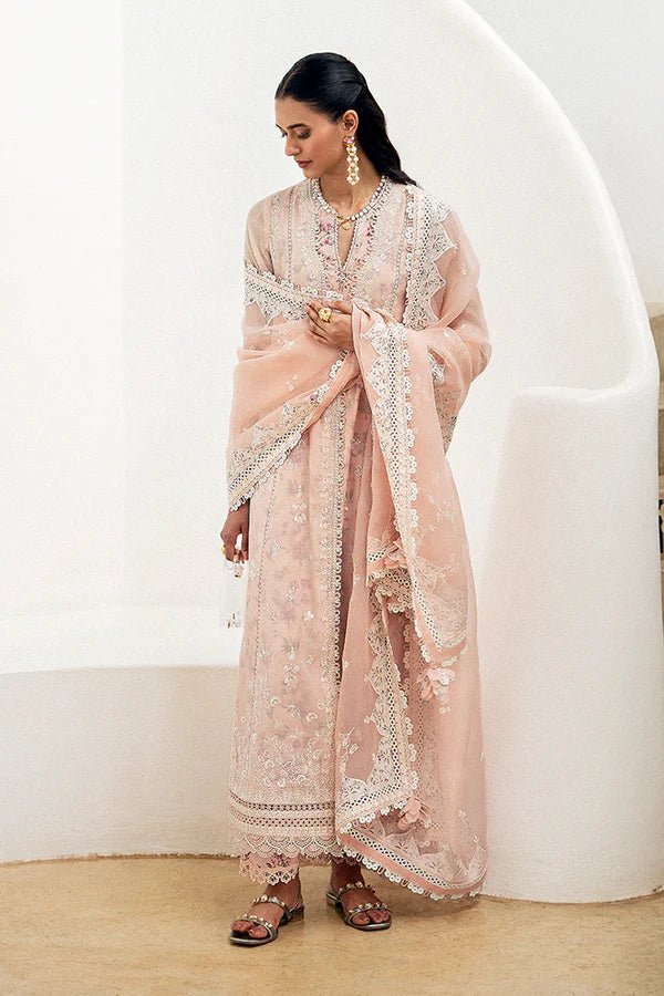 Model wearing a pastel peach flared overlapped double - layered shirt from Suffuse Casual Pret '24 collection, featuring white embroidery and lace detailing. Paired with printed cotton culottes and an organza dupatta. Available online in the UK.