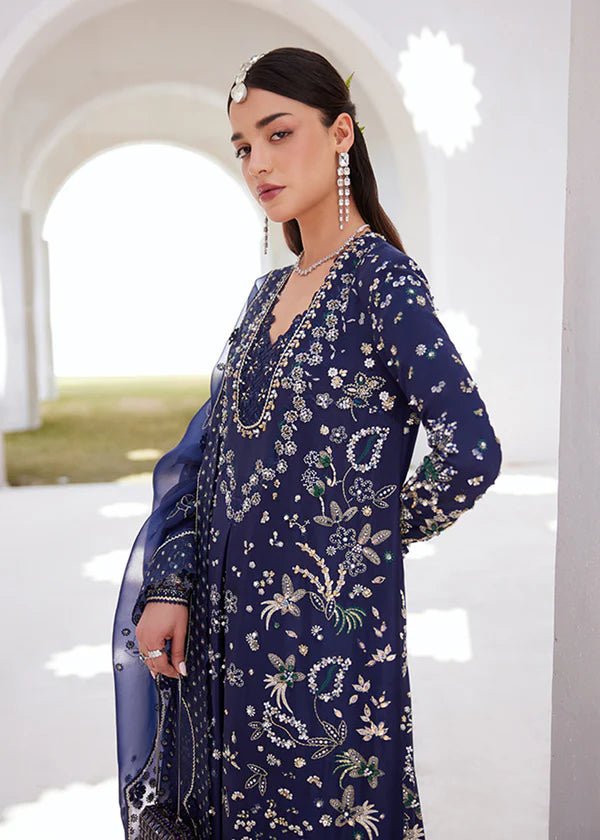 Model wearing a deep blue dress with intricate gold and green embroidery from the Suffuse FREESHIA RTW '24 Aroosh collection. Perfect for weddings. Pakistani clothes online in UK.