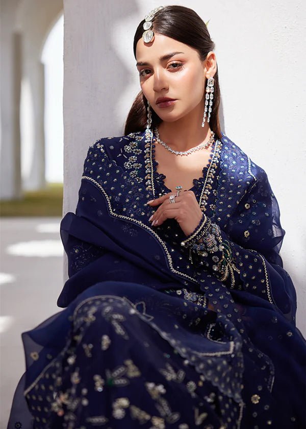 Model wearing a deep blue dress with intricate gold and green embroidery from the Suffuse FREESHIA RTW '24 Aroosh collection. Perfect for weddings. Pakistani clothes online in UK.