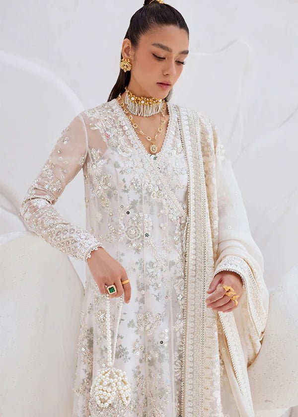 Model wearing an Model wearing a cream Yasna dress from Suffuse, showcasing intricate embroidery and embellishments. Ideal for wedding attire, available in the UK.