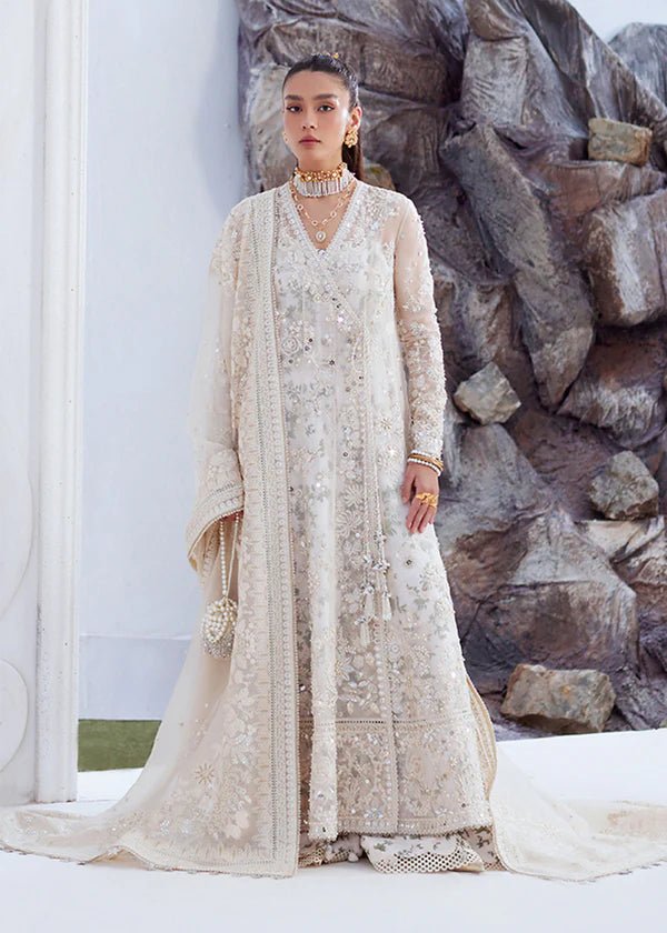 Model wearing an Model wearing a cream Yasna dress from Suffuse, showcasing intricate embroidery and embellishments. Ideal for wedding attire, available in the UK.