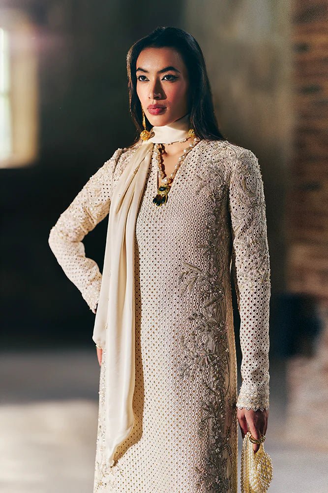 Model wearing Suffuse Silk Pret '24 Irana dress in ivory with intricate embellishments and delicate embroidery. Shop Pakistani bridal dresses online in the UK now.