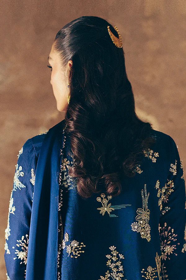 Model wearing dark blue Kira dress from Suffuse, adorned with golden embroidery, ideal for Eid and UK Pakistani fashion trends.