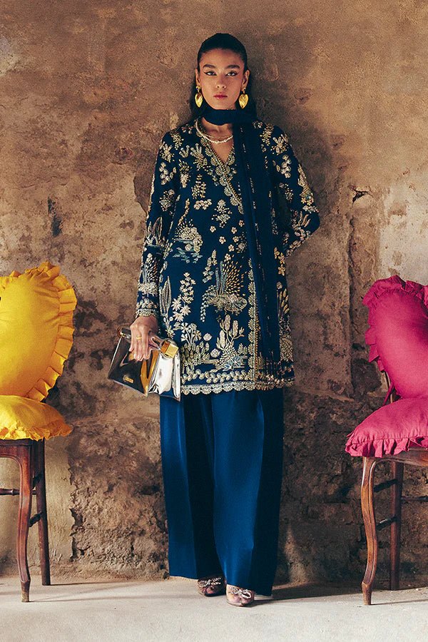 Model wearing dark blue Kira dress from Suffuse, adorned with golden embroidery, ideal for Eid and UK Pakistani fashion trends.